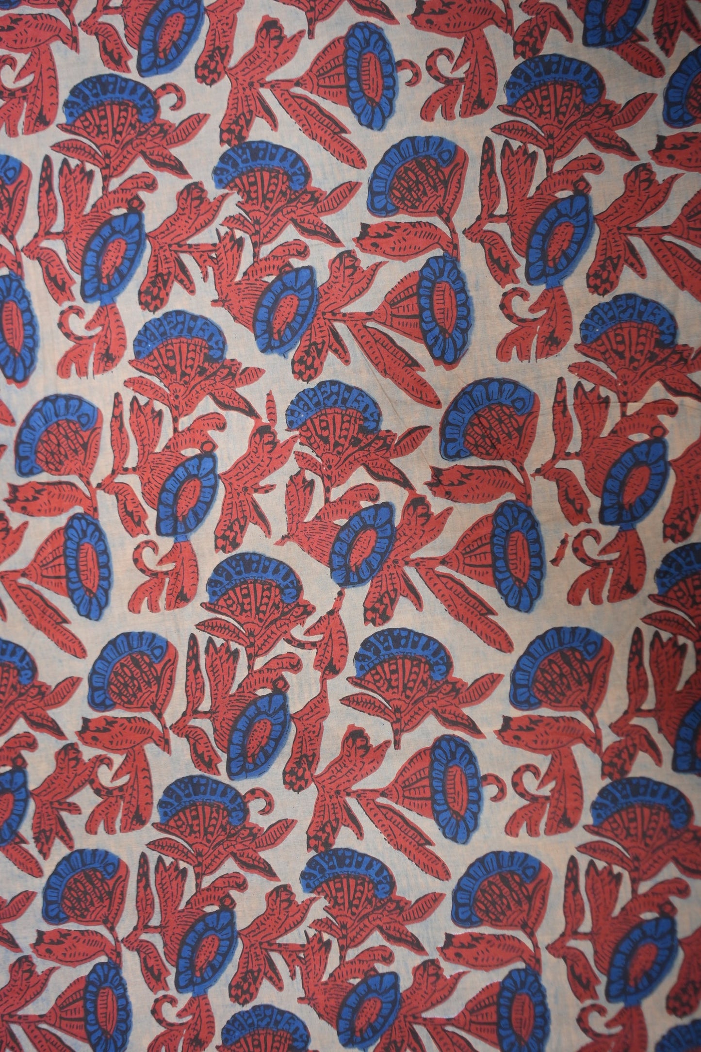 Patterned fabric with red and blue designs on a beige background