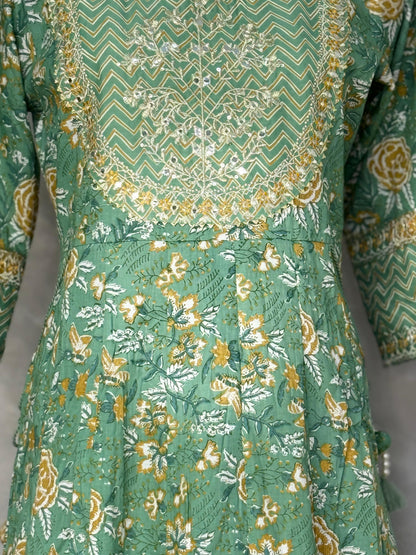 Green dress with floral and geometric patterns on a plain background