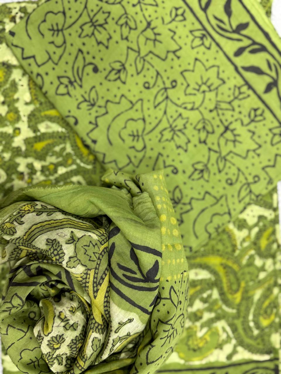 Green fabric with black floral patterns on a white background