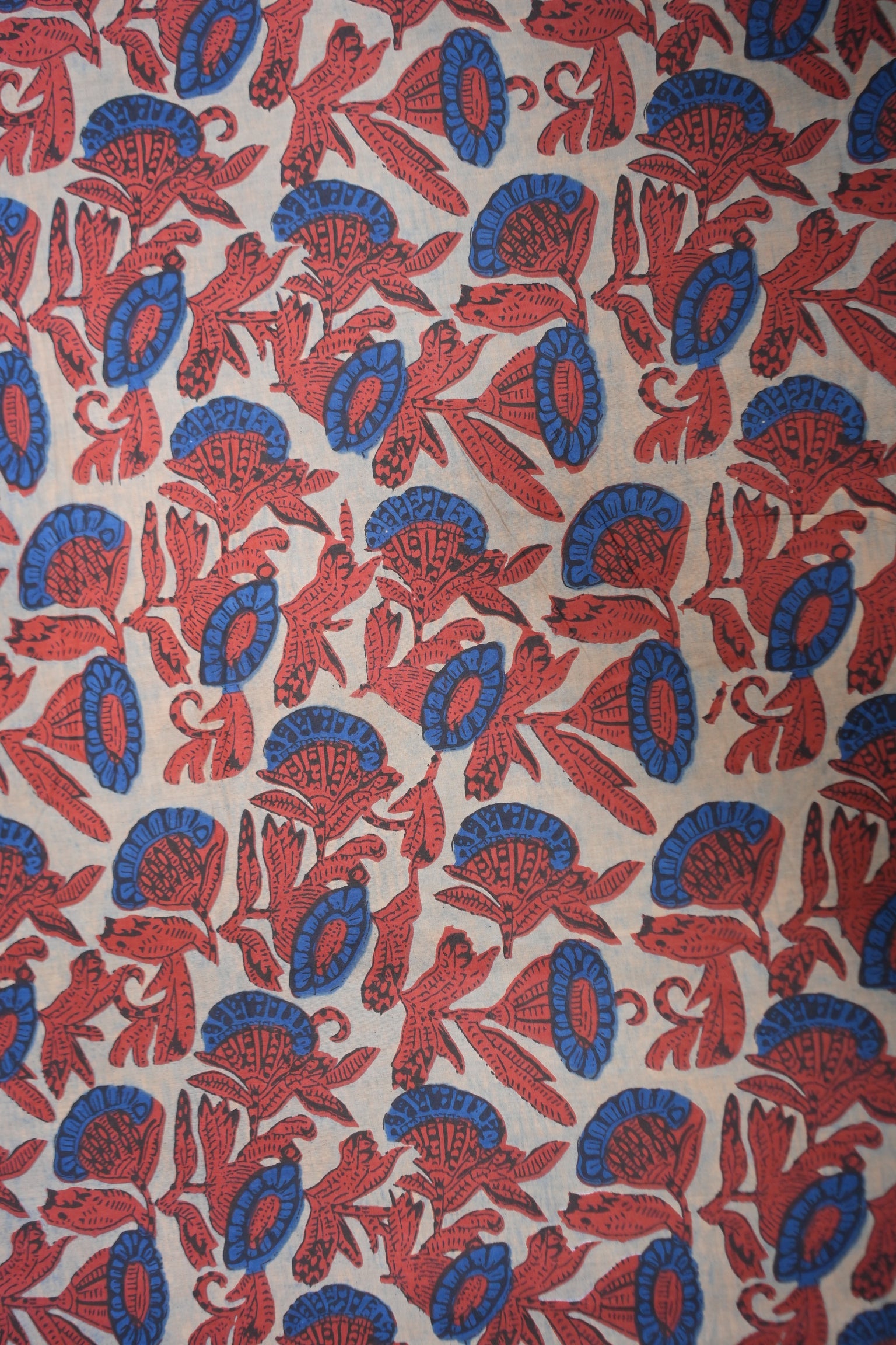 Patterned fabric with red and blue designs on a beige background