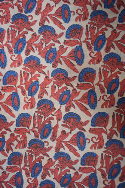 Patterned fabric with red and blue designs on a beige background