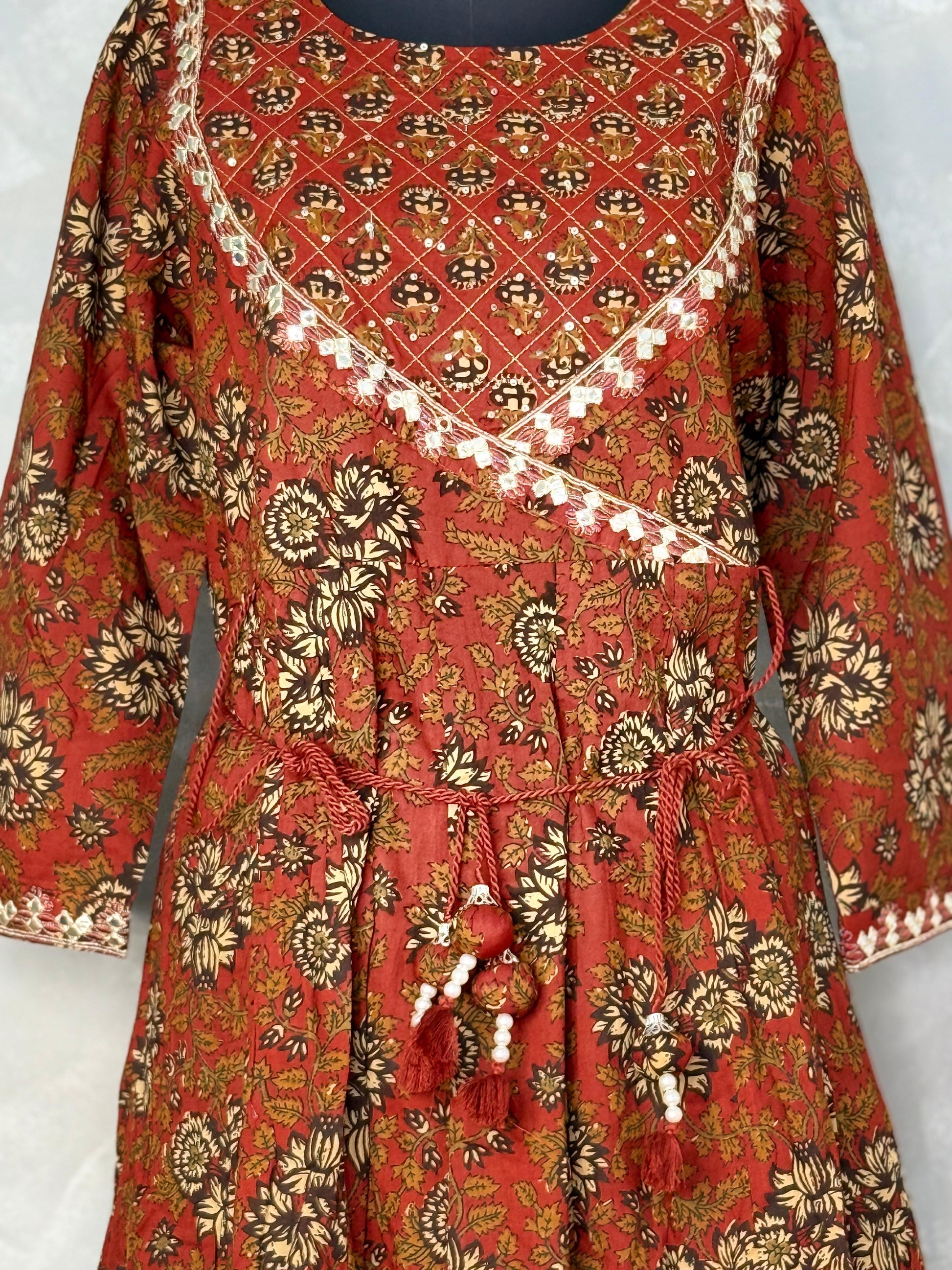 Red and gold patterned dress with tassels on a white background