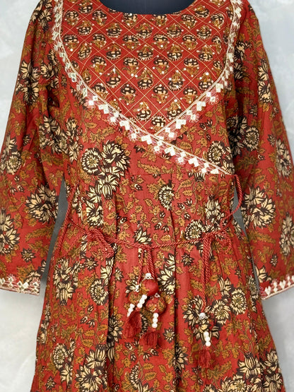 Red and gold patterned dress with tassels on a white background