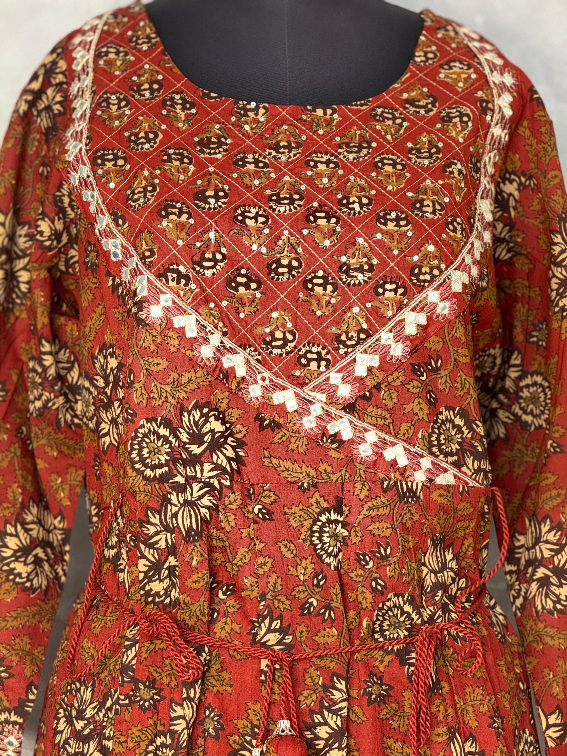 Red patterned dress with floral design on a mannequin against a white background
