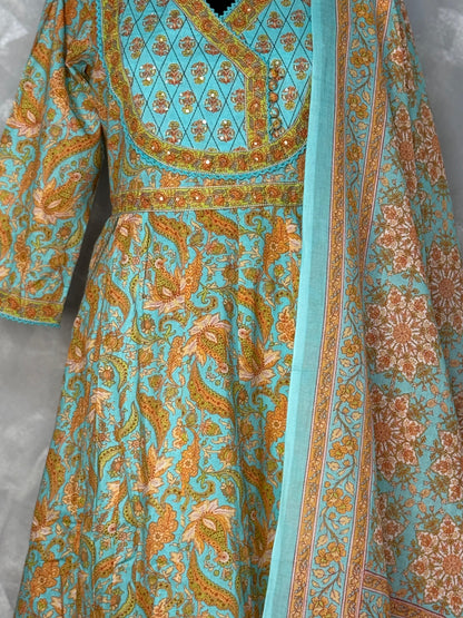 Turquoise and orange patterned dress with a matching sash on a gray background