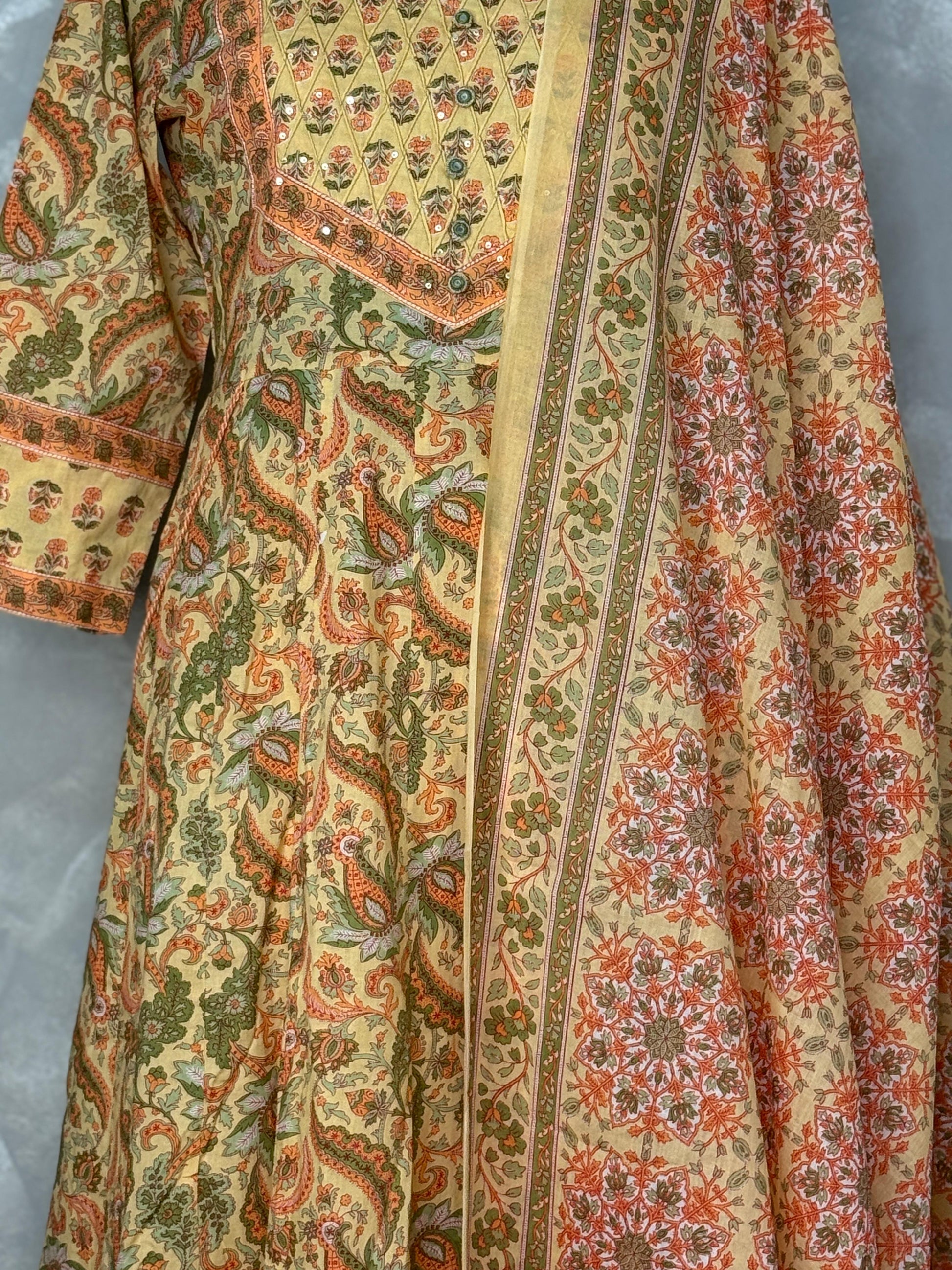 Yellow and white patterned dress on a mannequin against a gray background sujjis